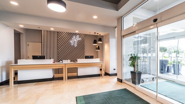 A reception area with a reception desk, a modern wall design, and a large glass door leading outside.