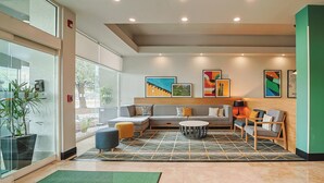 A modern lobby with a sectional sofa, a round coffee table, and a patterned rug.