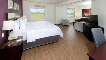 Ein Hotelzimmer mit Bett, Schreibtisch, Stuhl, Fernseher und einem Fenster mit Blick ins Freie.