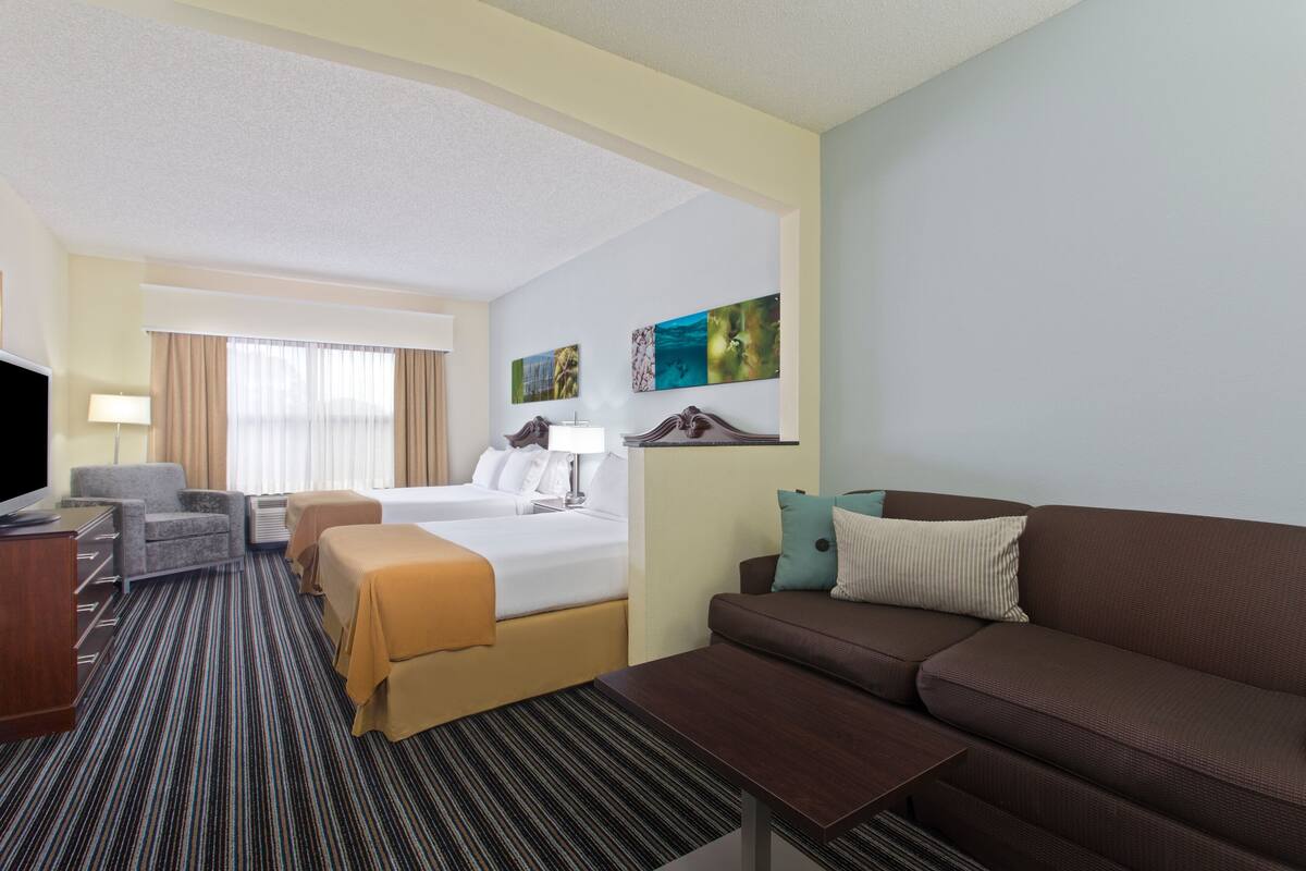 Ein Hotelzimmer mit Bett, Sofa, Schreibtisch und Fernseher.