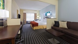 A hotel room with a bed, a sofa, a TV, and a desk.