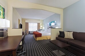 Ein Hotelzimmer mit Bett, Sofa, Fernseher und Schreibtisch.