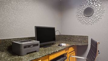 Escritório em casa com computador de mesa, impressora e espelho decorativo fixado na parede.