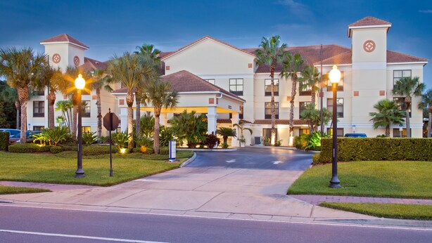 A hotel with a central courtyard, palm trees, and a well-lit entrance.