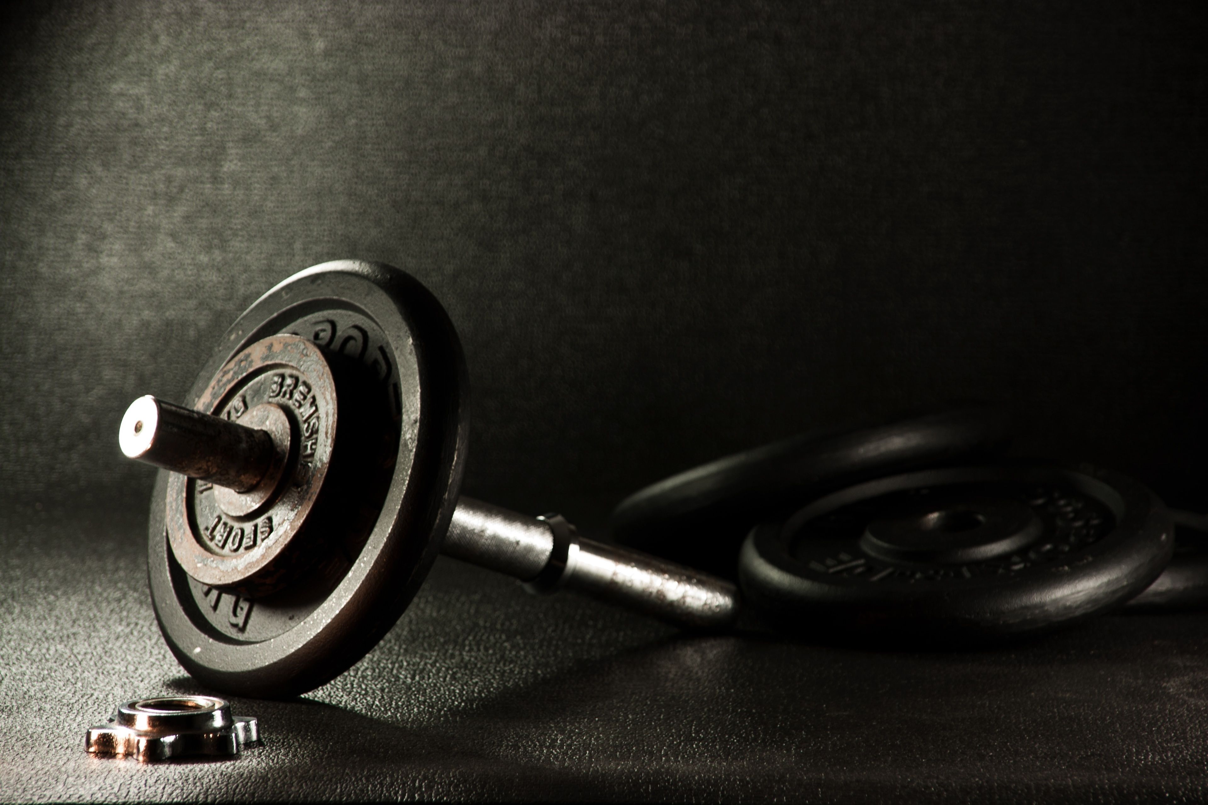 A weightlifting barbell with weights on a textured surface.
