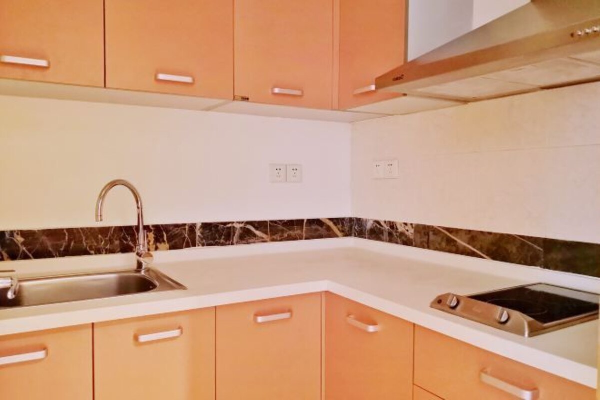 A kitchen with a sink, stove, and cabinets.