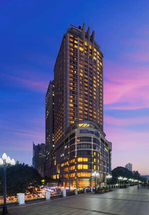 Un edificio de hotel alto con ventanas iluminadas y un logotipo Hilton destacado.
