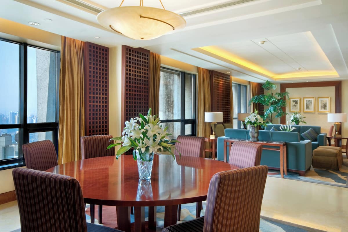 Een ruime hotellobby met een grote ronde tafel, comfortabele zithoek en grote ramen met uitzicht over de stad.