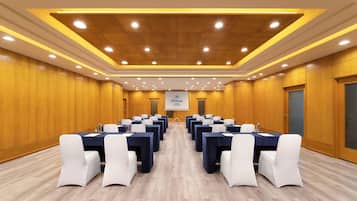 A conference room with multiple tables and chairs, a podium, and a screen displaying the Hilton logo.