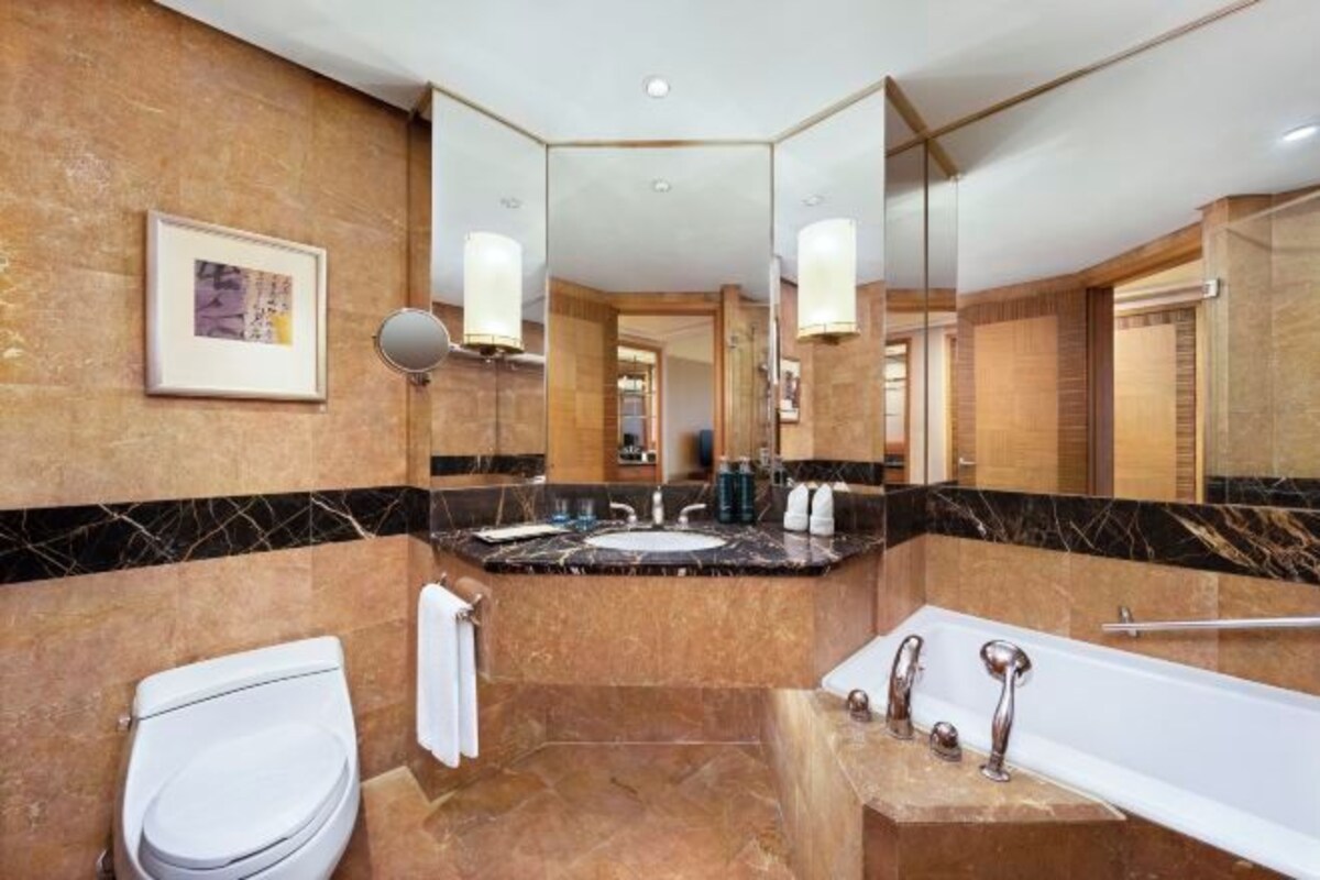 A modern bathroom with a marble sink, a bathtub, and a toilet.