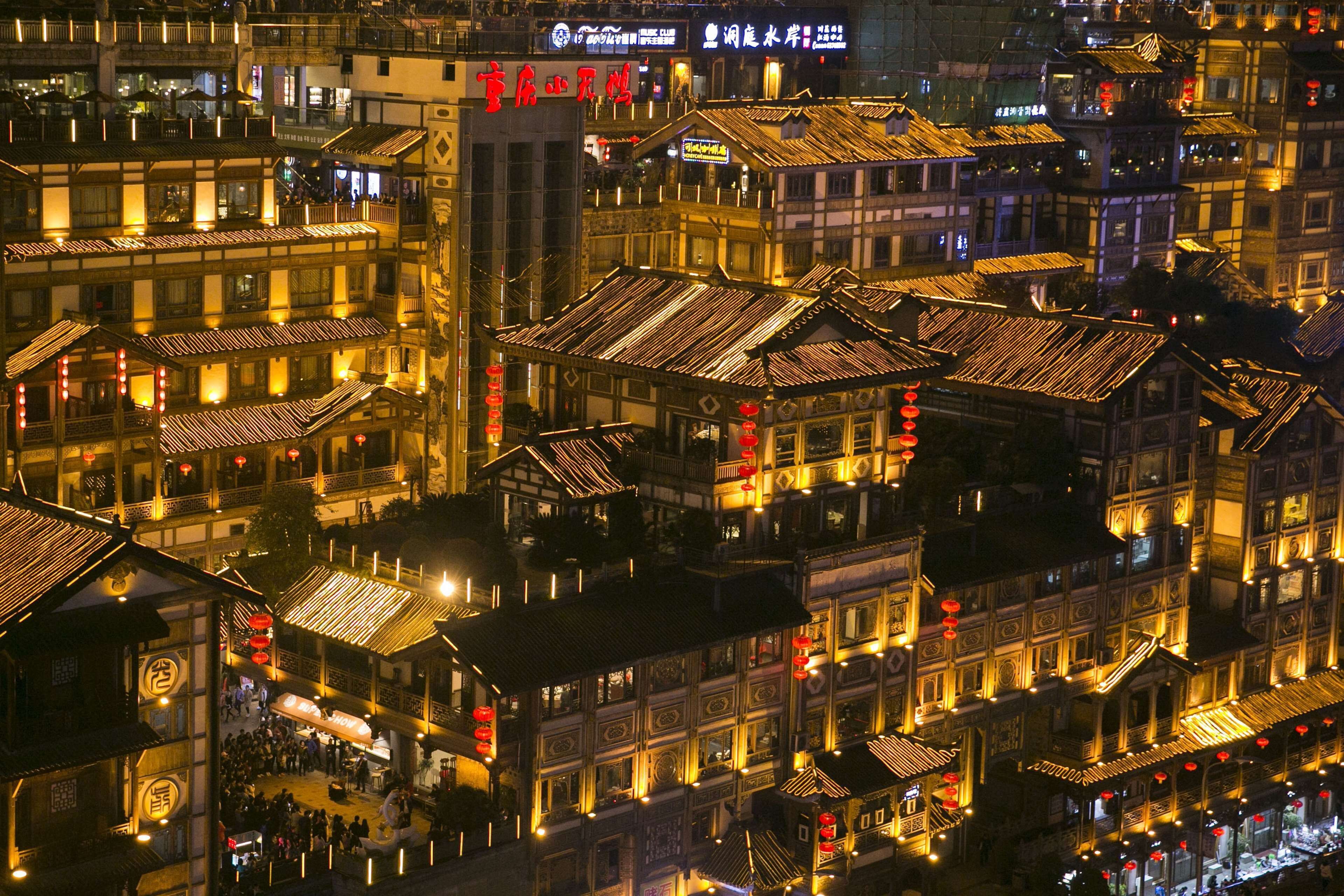 A traditional multi-story building with a prominent red sign, multiple balconies, and a bustling street scene below.