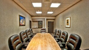 Un salón de conferencias con una larga mesa de madera y ocho sillas de cuero.