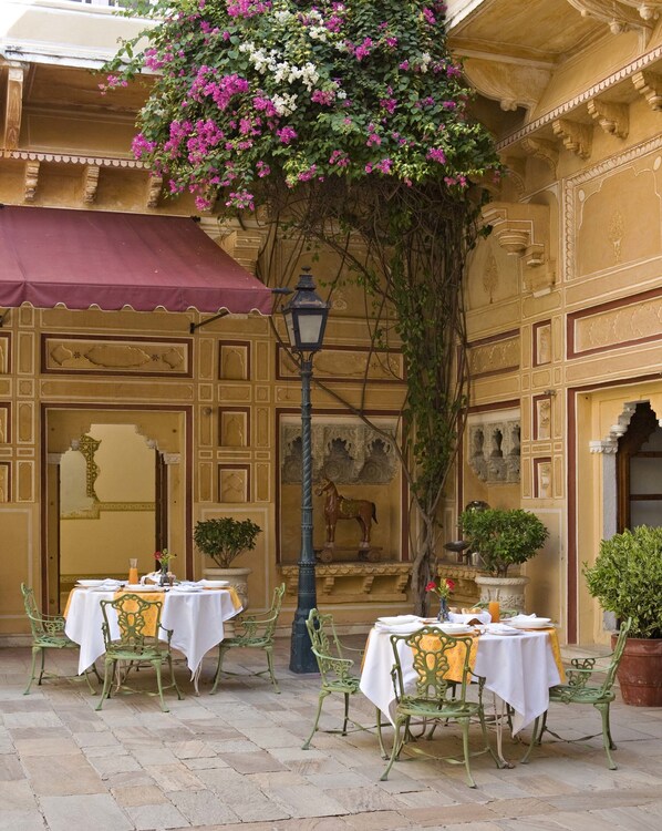An outdoor dining area with tables and chairs, a statue, and a decorative lamp.
