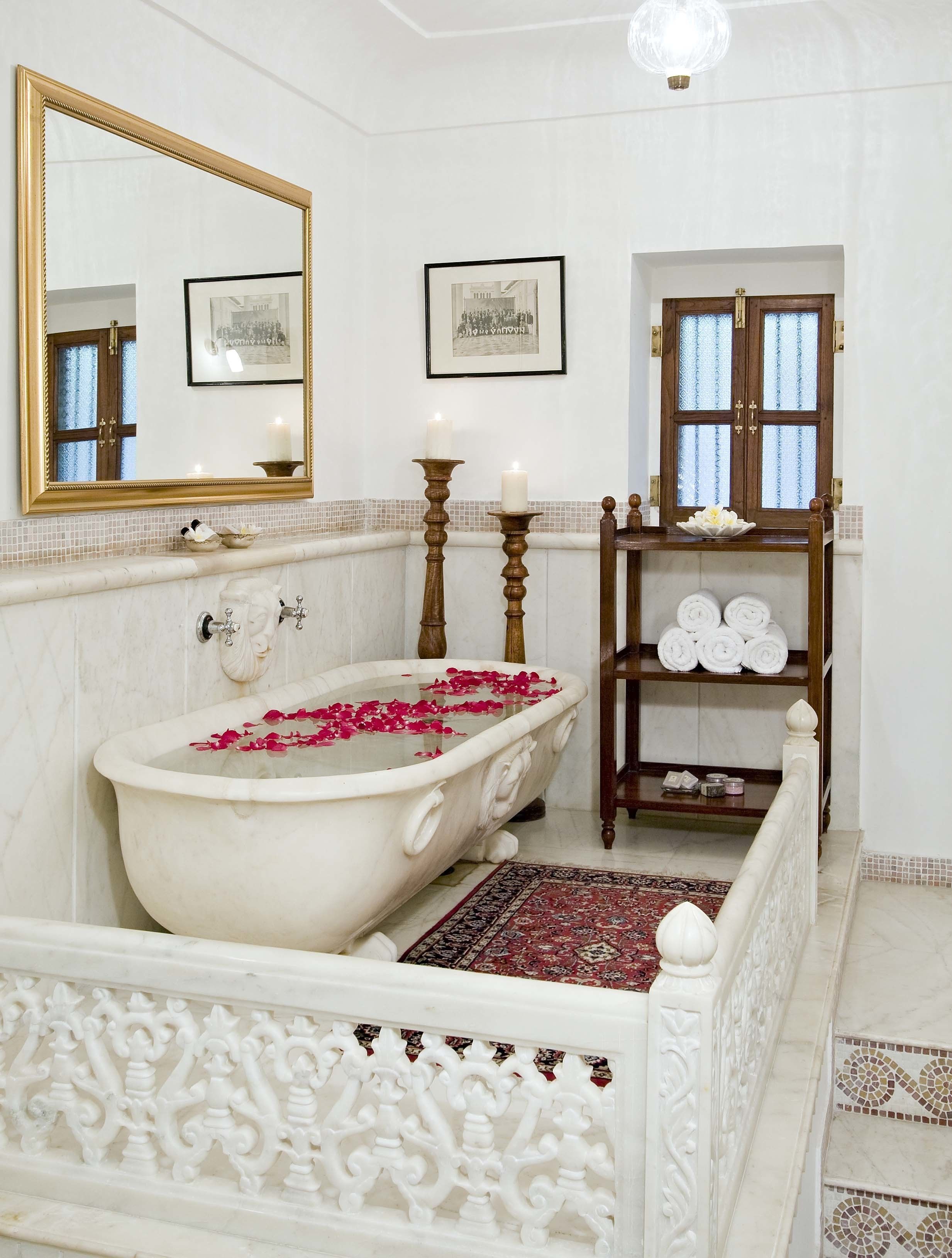 Un baño clásico con una bañera independiente, un espejo grande y un tocador de madera con toallas.