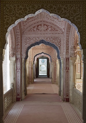 An ornate hallway with intricate arches and detailed patterns on the walls and ceiling.