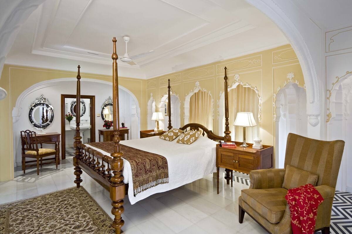 Um quarto espaçoso com uma cama de dossel, uma cadeira de madeira e uma mesa de cabeceira com abajur.