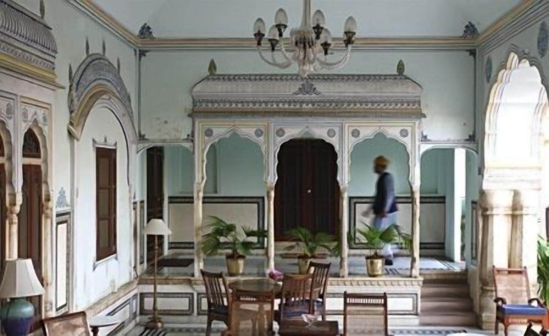 Una habitación con candelabro, una mesa con sillas y plantas en macetas.