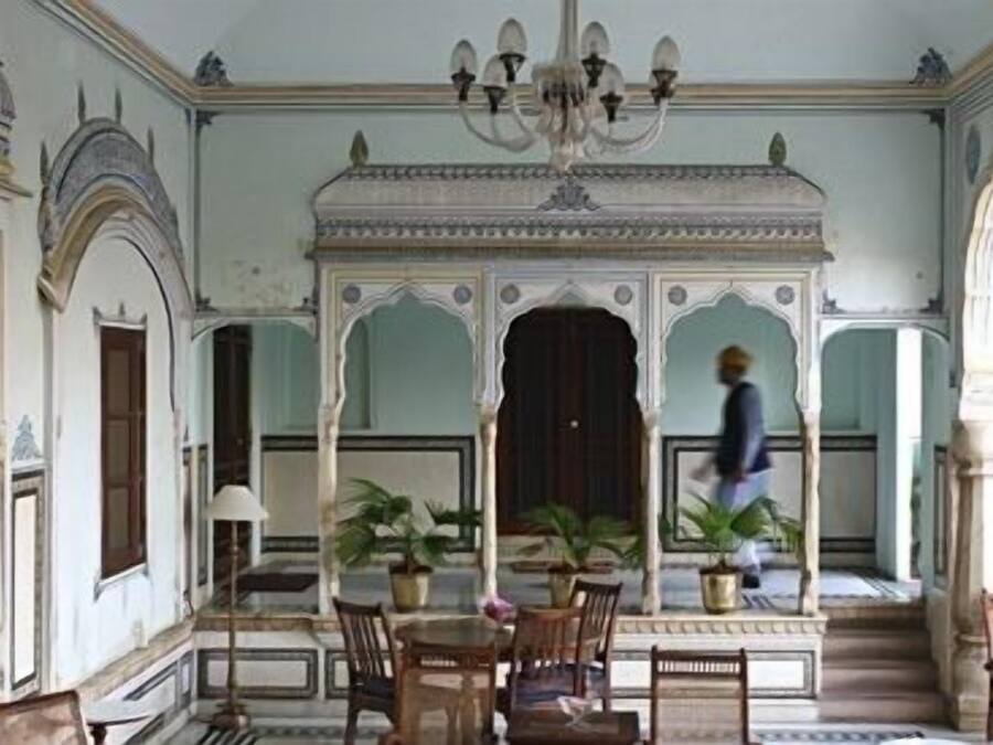Una habitación con candelabro, una mesa con sillas y plantas en macetas.