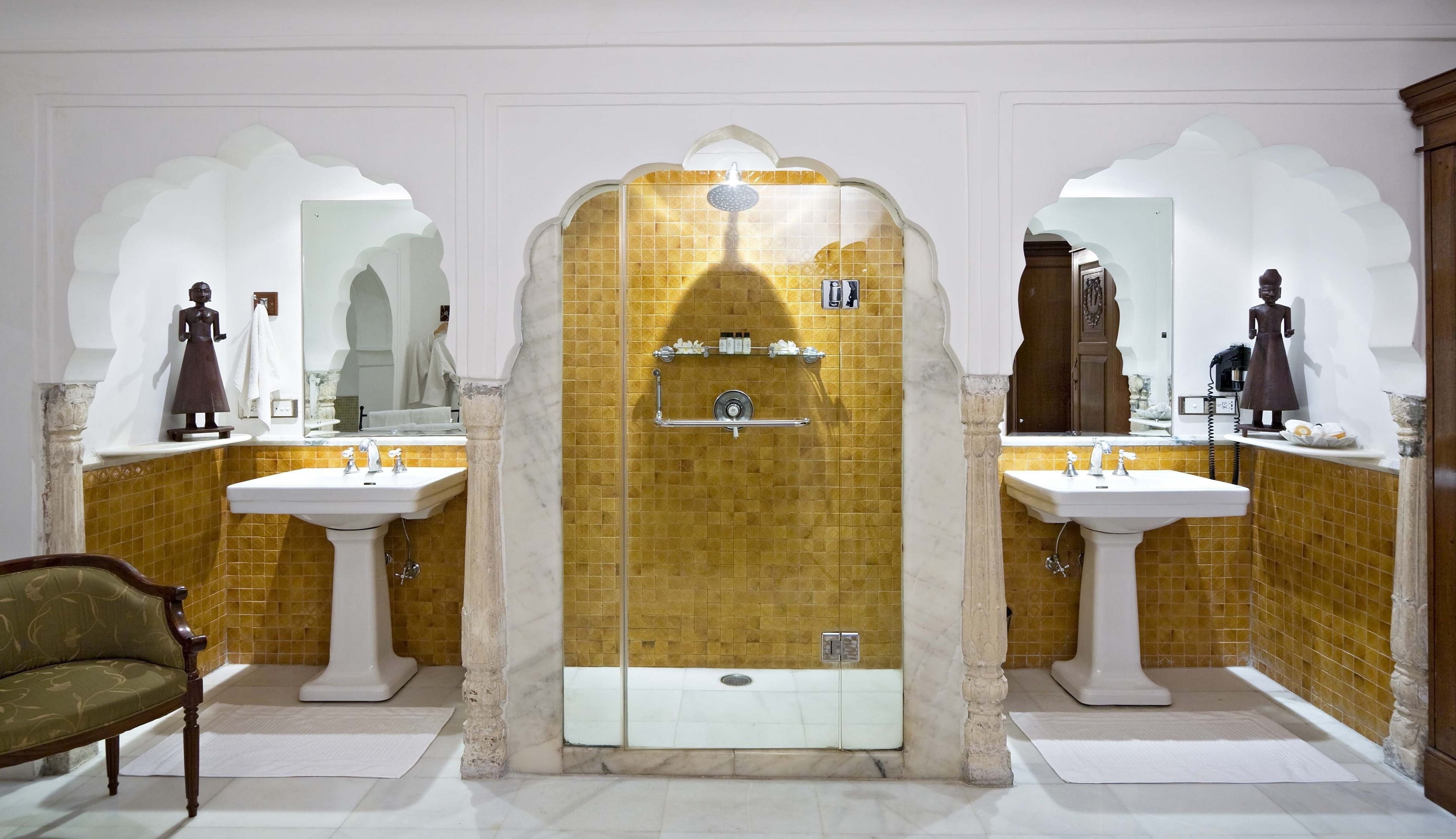 Un baño con dos lavamanos, ducha y espejos decorativos.