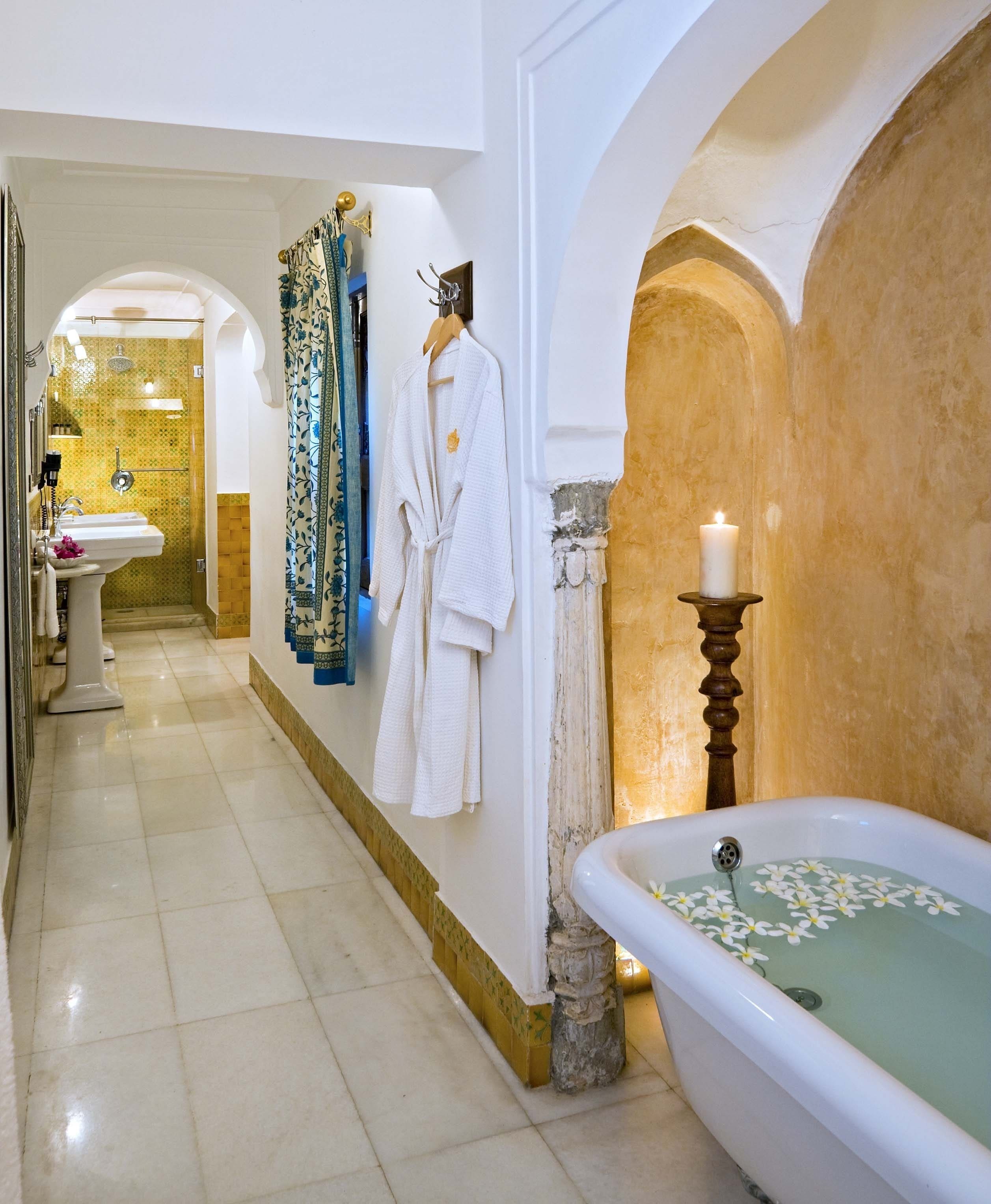 A bathroom with a bathtub, a sink, and a shower. There are towels and robes hanging on the wall.
