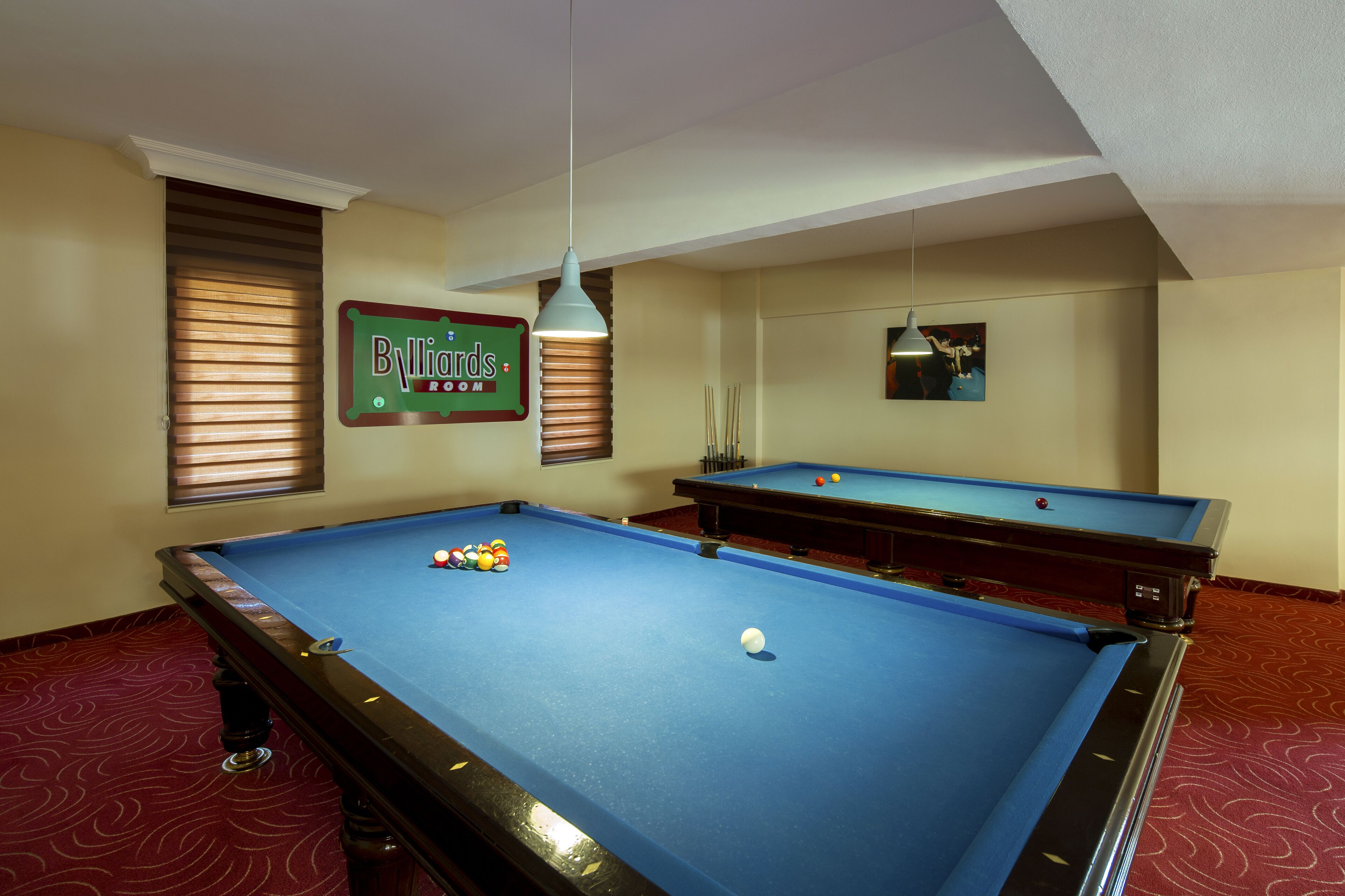 A pool table with balls, a billiard cue, and a sign reading "Billiards Room".