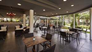 An outdoor dining area with wicker furniture, a wooden table, and a red chandelier. - Richmond Ephesus Resort - All Inclusive (Selçuk)