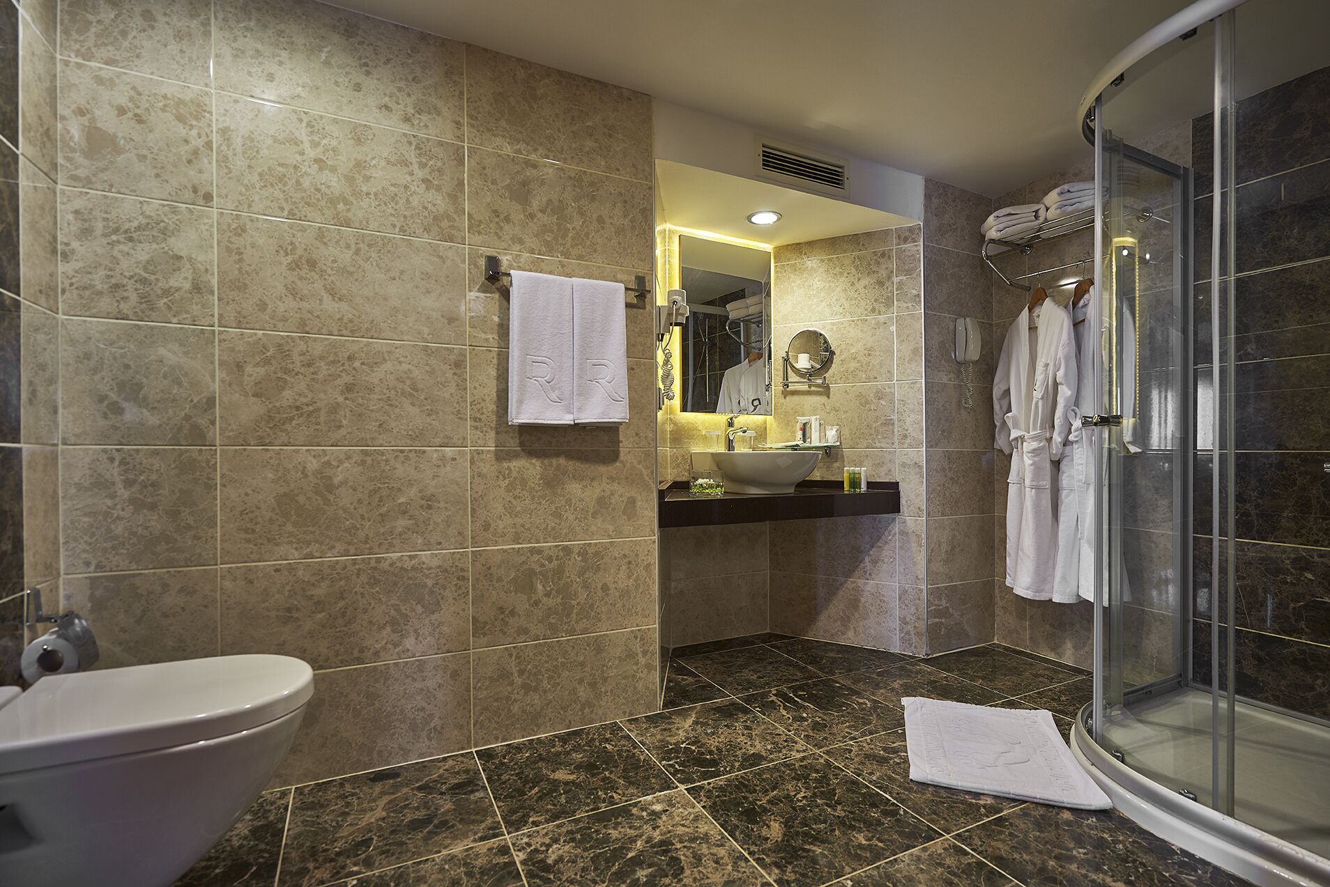 A bathroom with a toilet, sink, mirror, and shower.