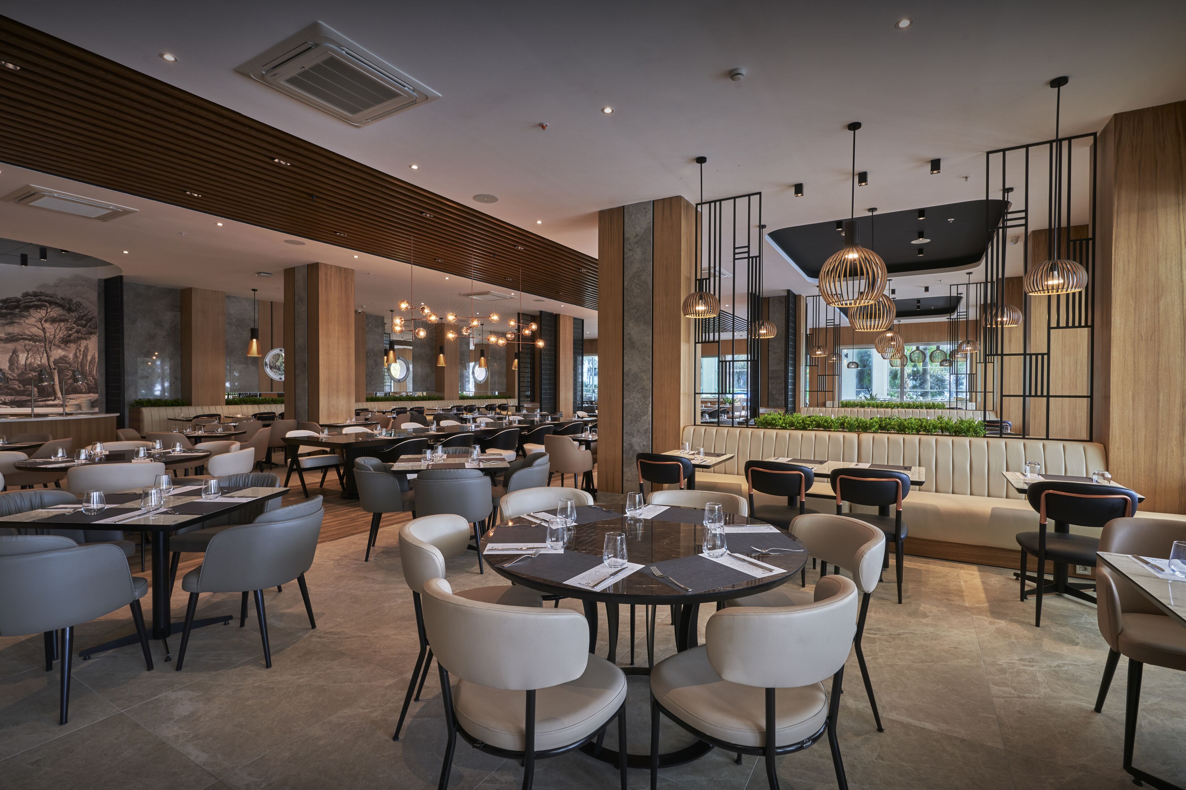 A modern restaurant with round tables, high chairs, and pendant lighting.