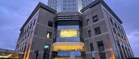 A tall, modern hotel with a prominent entrance and a large sculpture in front.