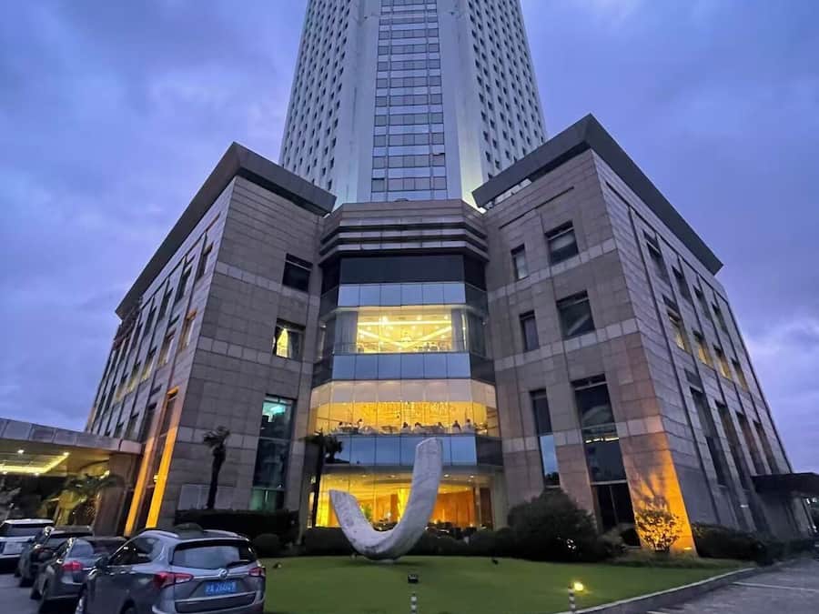 A tall, modern hotel with a prominent entrance and a large sculpture in front.