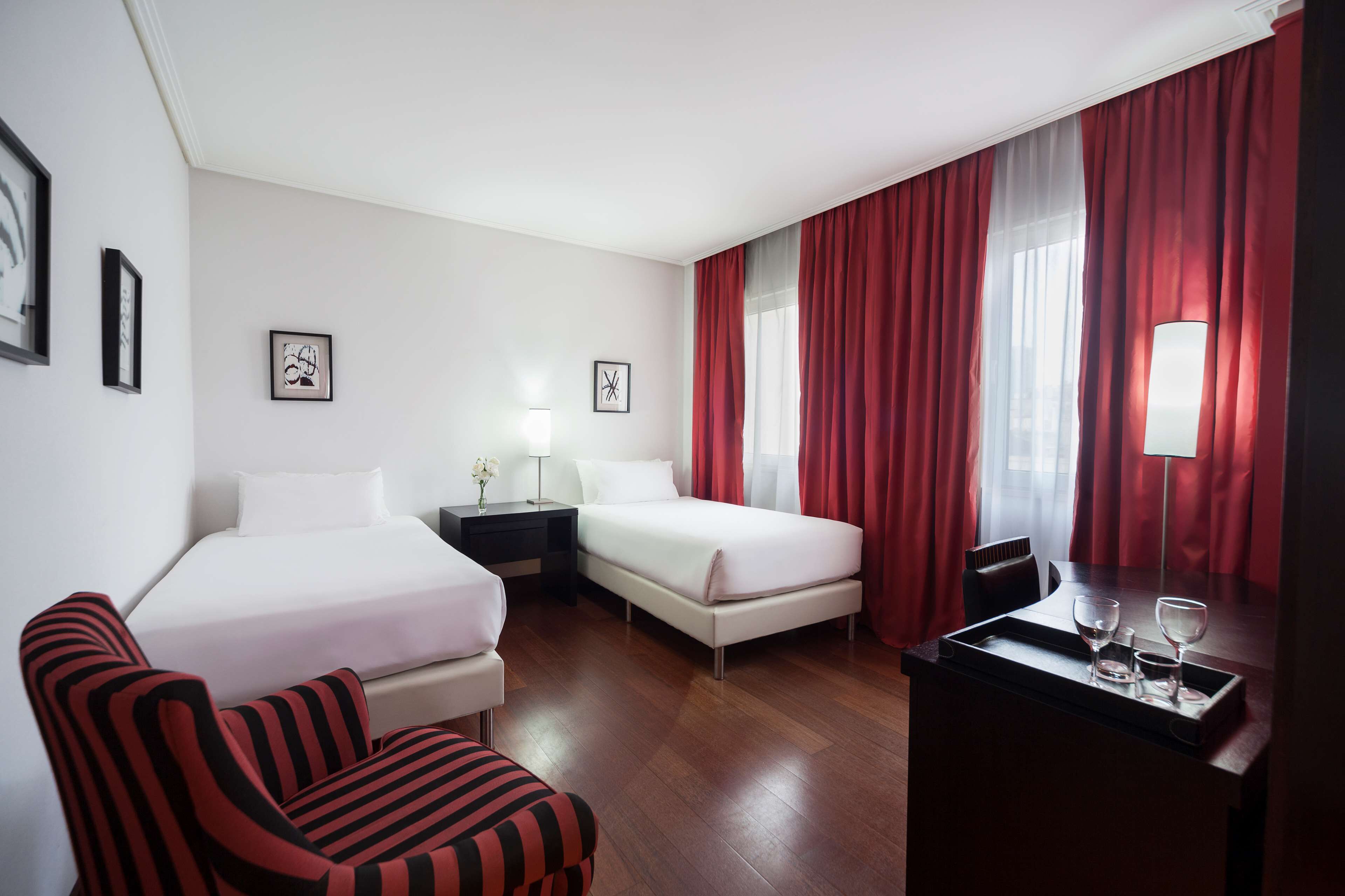 Habitación de hotel con dos camas, un escritorio con bandeja y una silla.