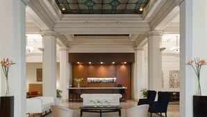 Un vestíbulo con una recepción, un sofá blanco, dos sillones y una mesa de centro.