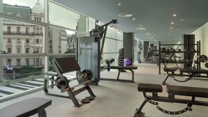 Un gimnasio moderno con diverso equipo de ejercicio, amplias ventanas con vistas a la ciudad y un diseño espacioso.