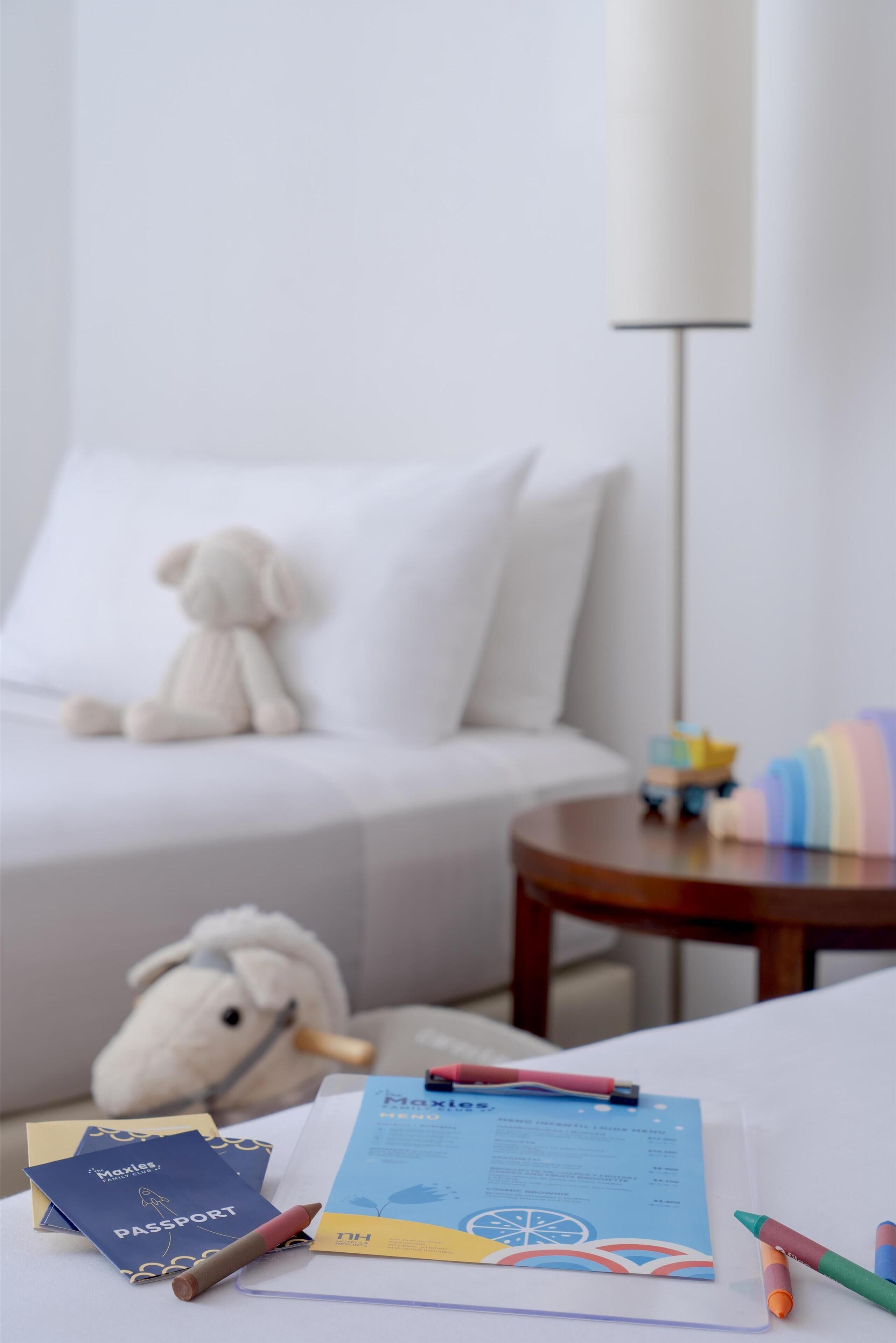 Una habitación ordenada con un sofá blanco, una mesita redonda con una lámpara y un peluche.