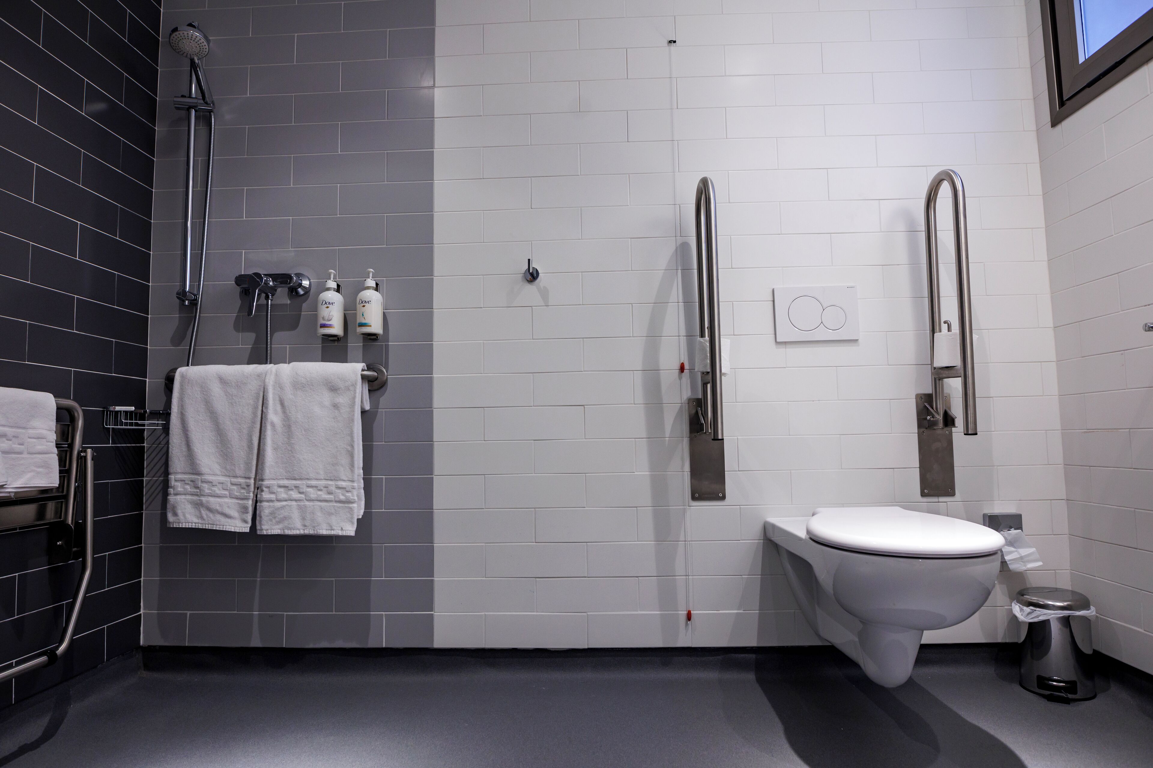 Une salle de bain moderne équipée d’une douche, de toilettes et d’un sèche-mains.