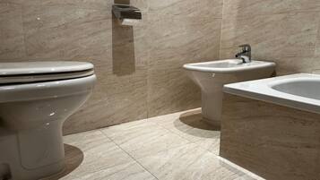 A modern bathroom with a toilet, bidet, and sink.