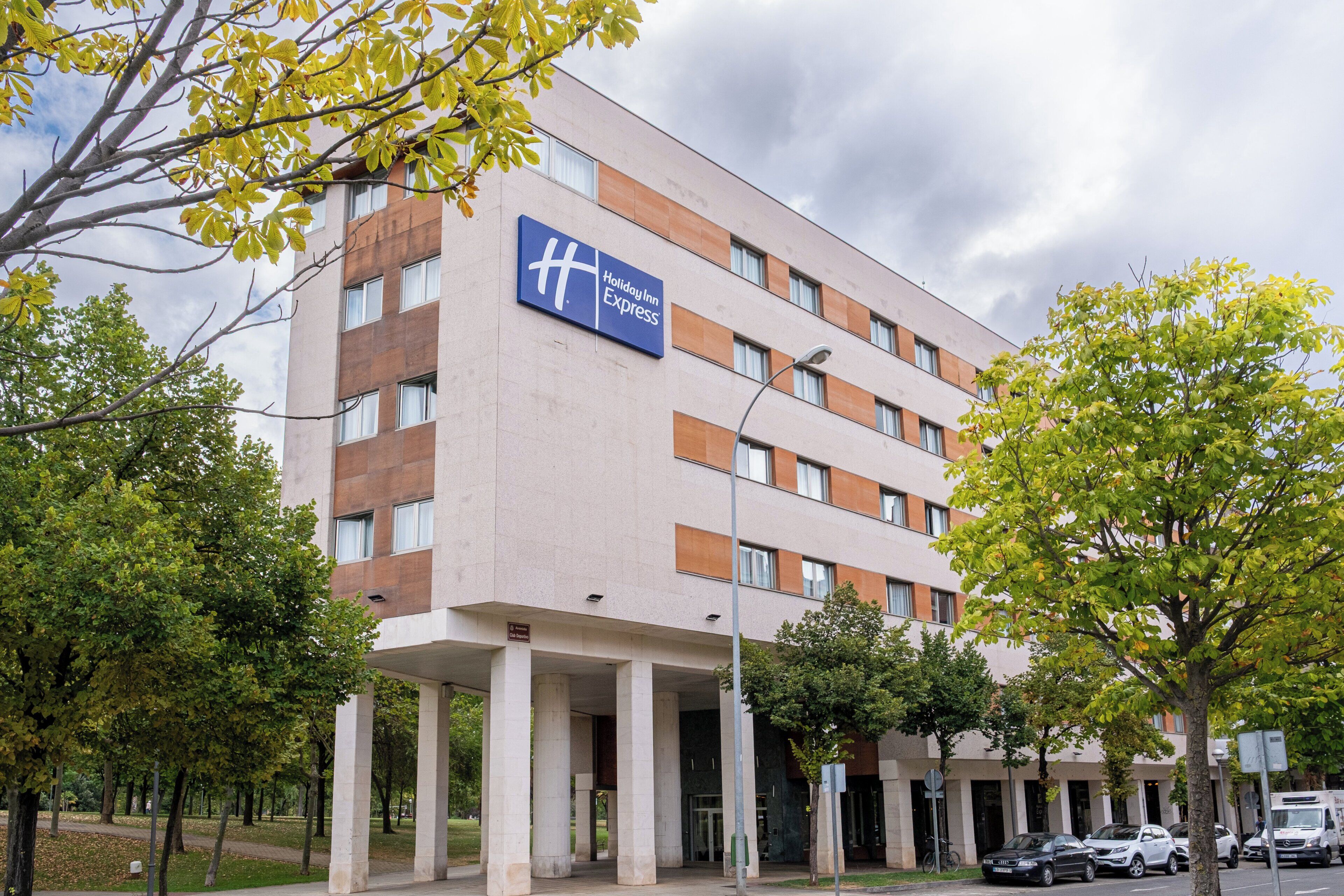 Edificio de Holiday Inn Express con un diseño arquitectónico moderno, que presenta un letrero llamativo, ventanas amplias y una zona de entrada cubierta.