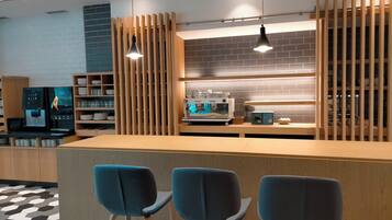 Un área de cocina moderna con cafetera, taburetes de bar y listones de madera.