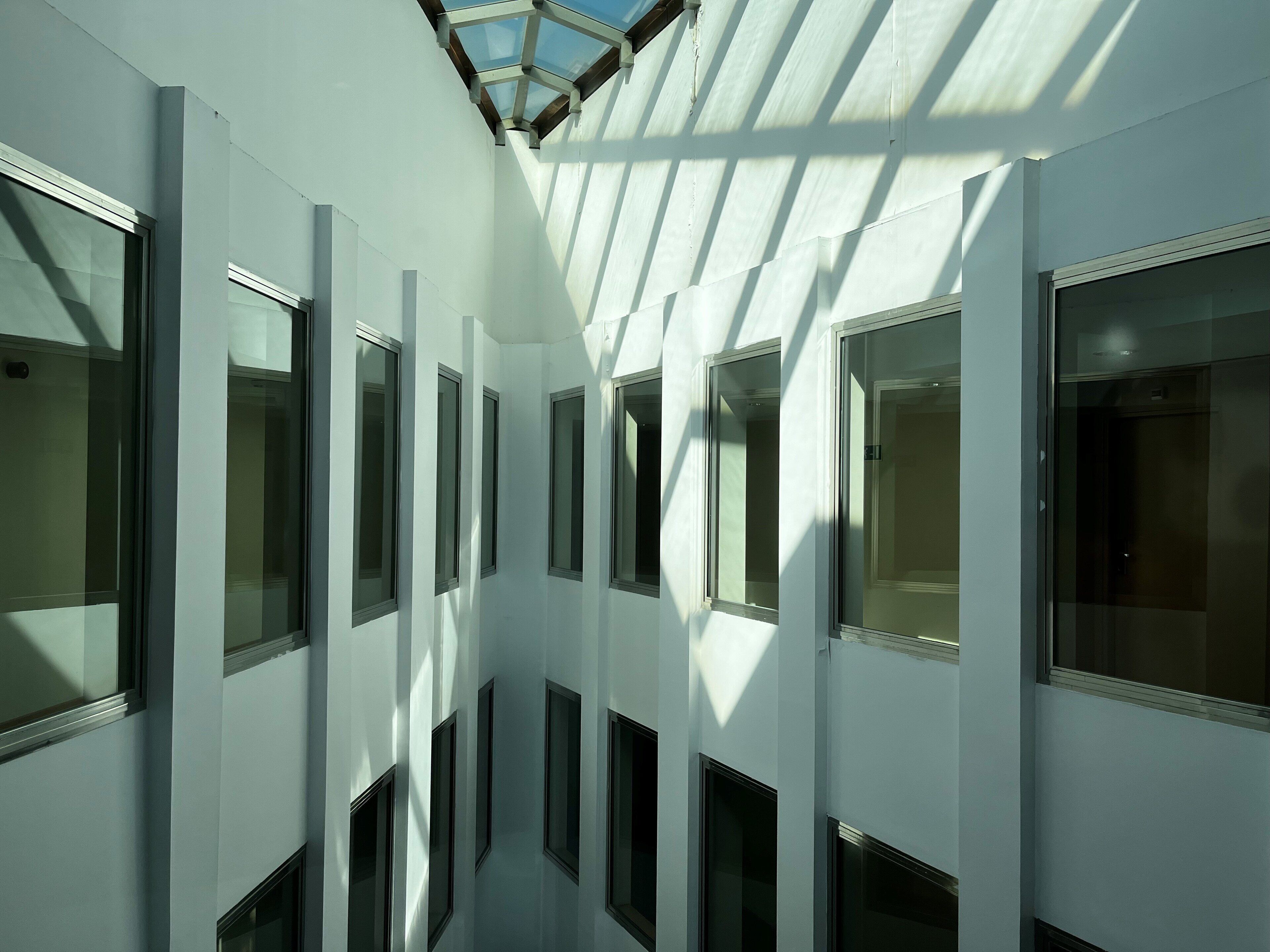 Een modern gebouw met een centrale gang aan beide zijden begrensd door ramen en een dakraam.