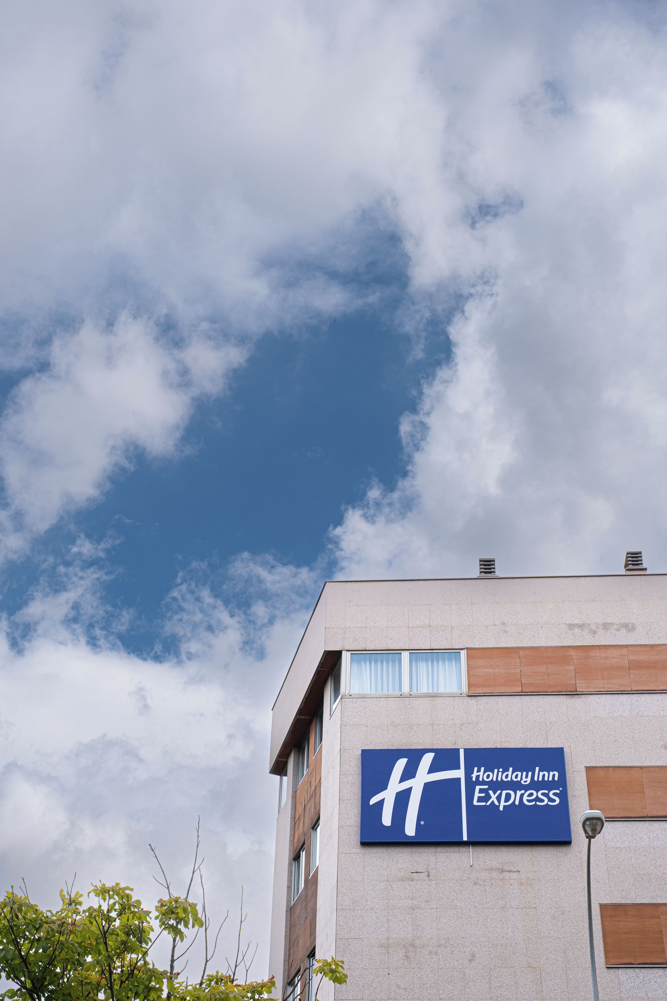 Un letrero de Holiday Inn Express en un edificio, con cielo despejado y algunas nubes.