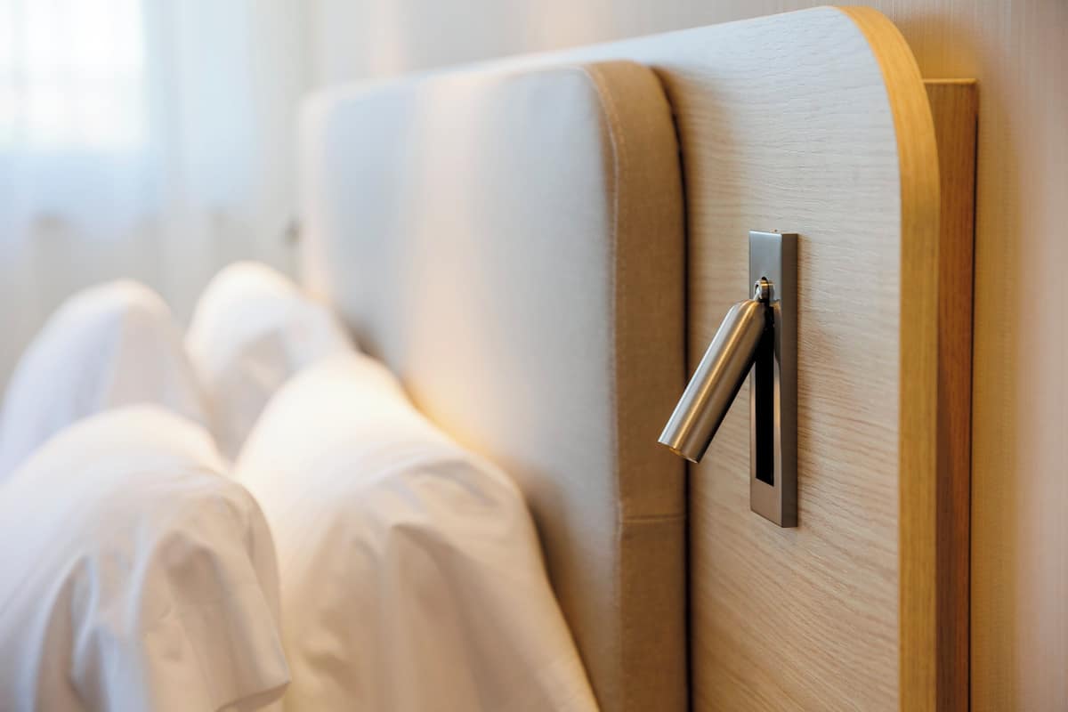 Habitación de hotel con cabecera de madera y pomo metálico.