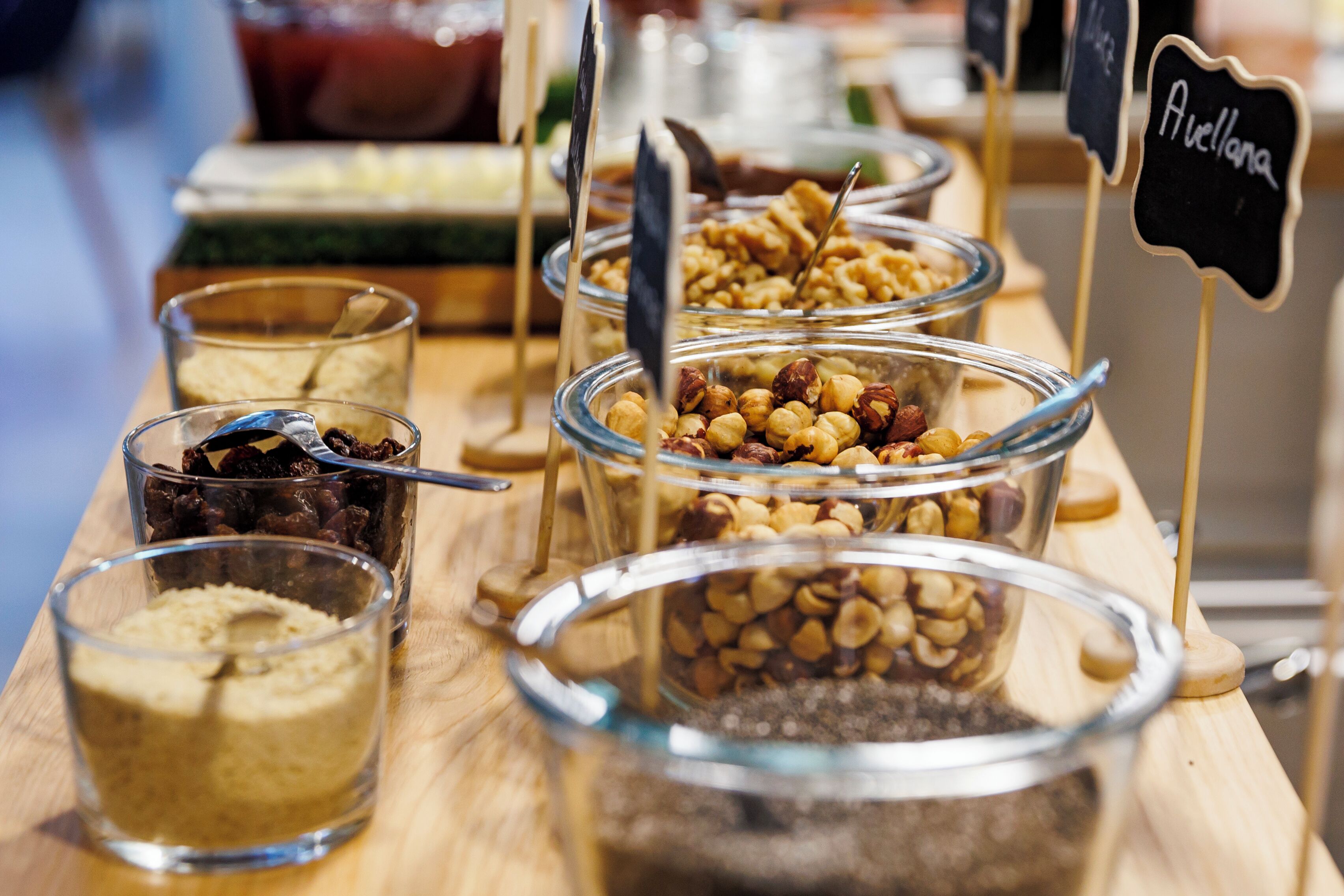 A buffet table with various food items in glass containers, including nuts and dried fruits.