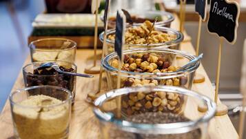 A buffet table with various food items in glass containers, including nuts and dried fruits.