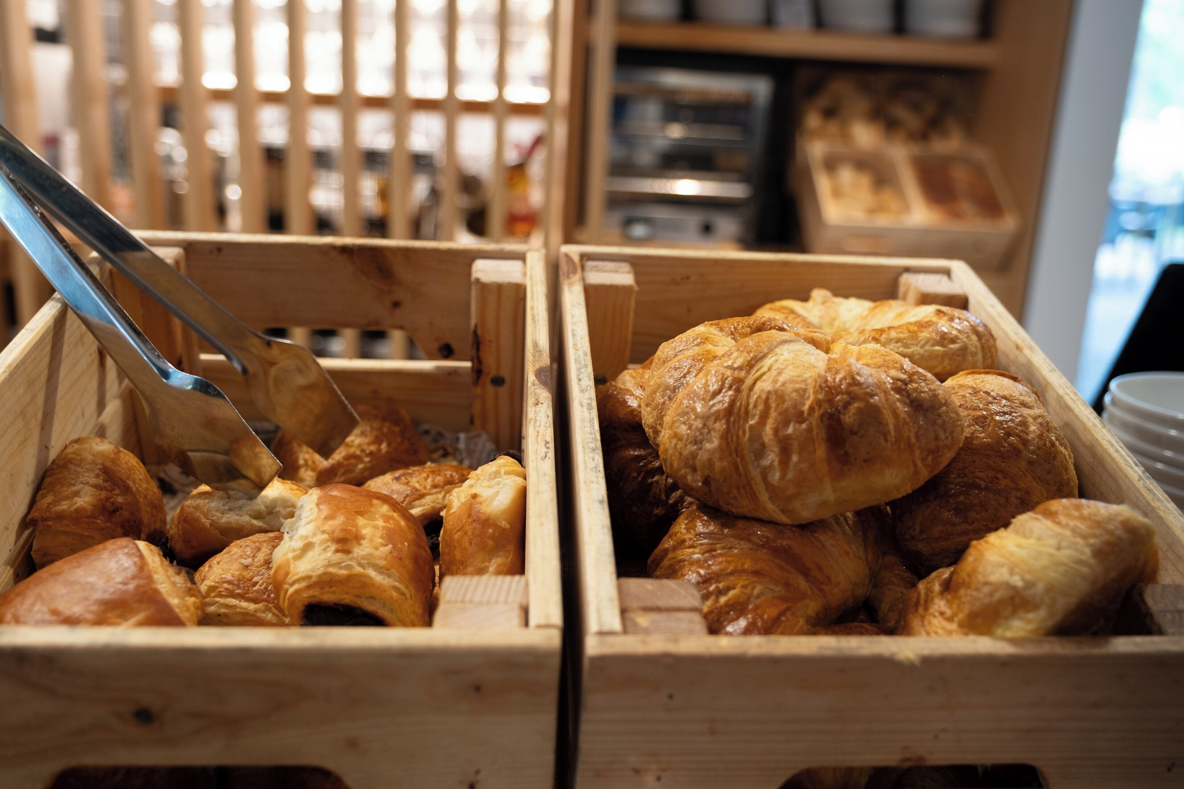 Two wooden crates filled with various types of pastries, including croissants and other baked goods.