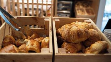 Dos cajas de madera repletas de diversos tipos de pasteles, incluyendo croissants y otras delicias horneadas.