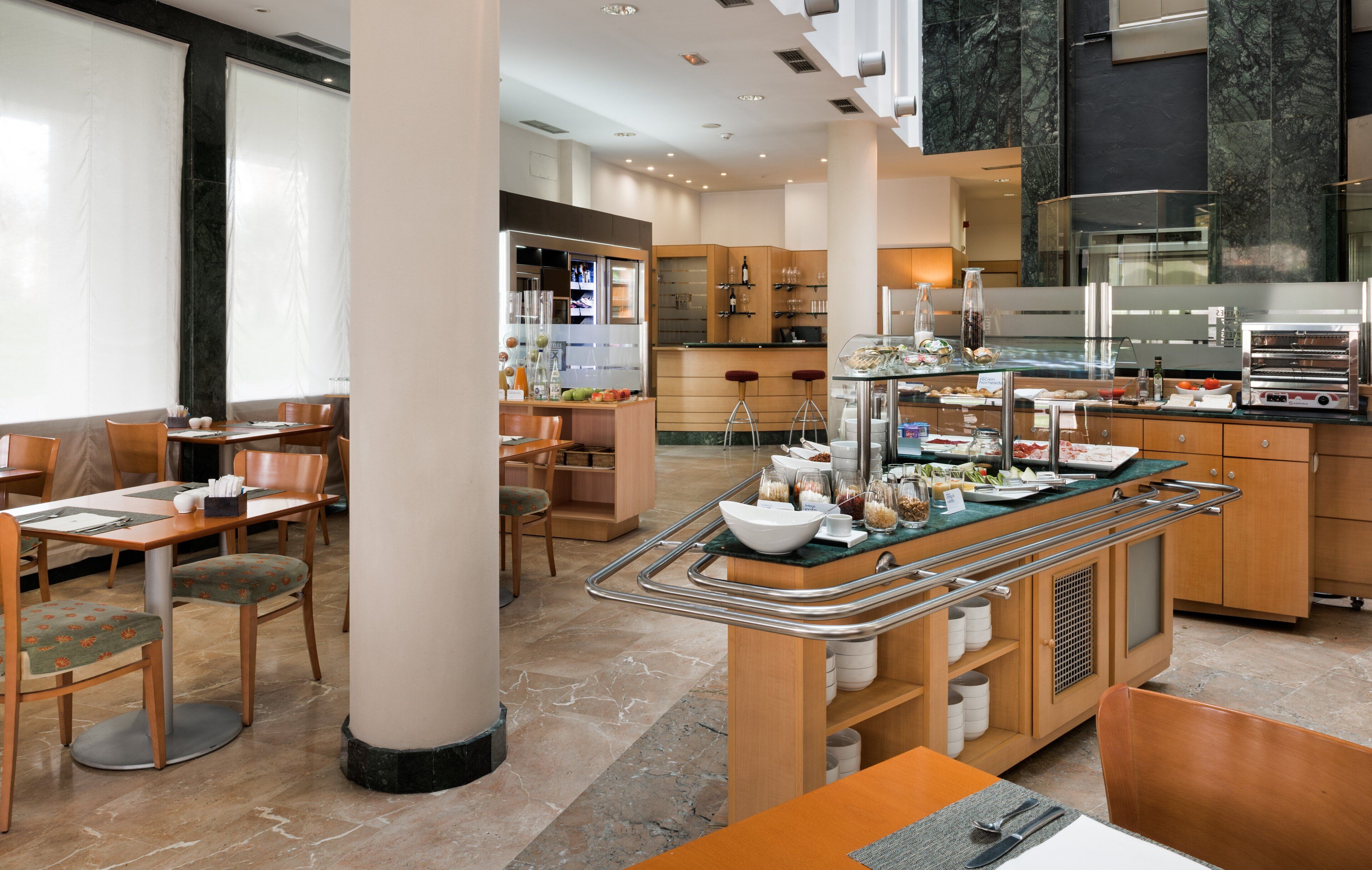 A modern restaurant with a buffet setup, wooden furniture, and a marble floor.