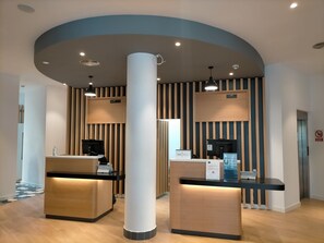 A reception area with two counters, a large central column, and a ceiling with recessed lighting. - Holiday Inn Express Logrono Rioja by IHG (Logroño)