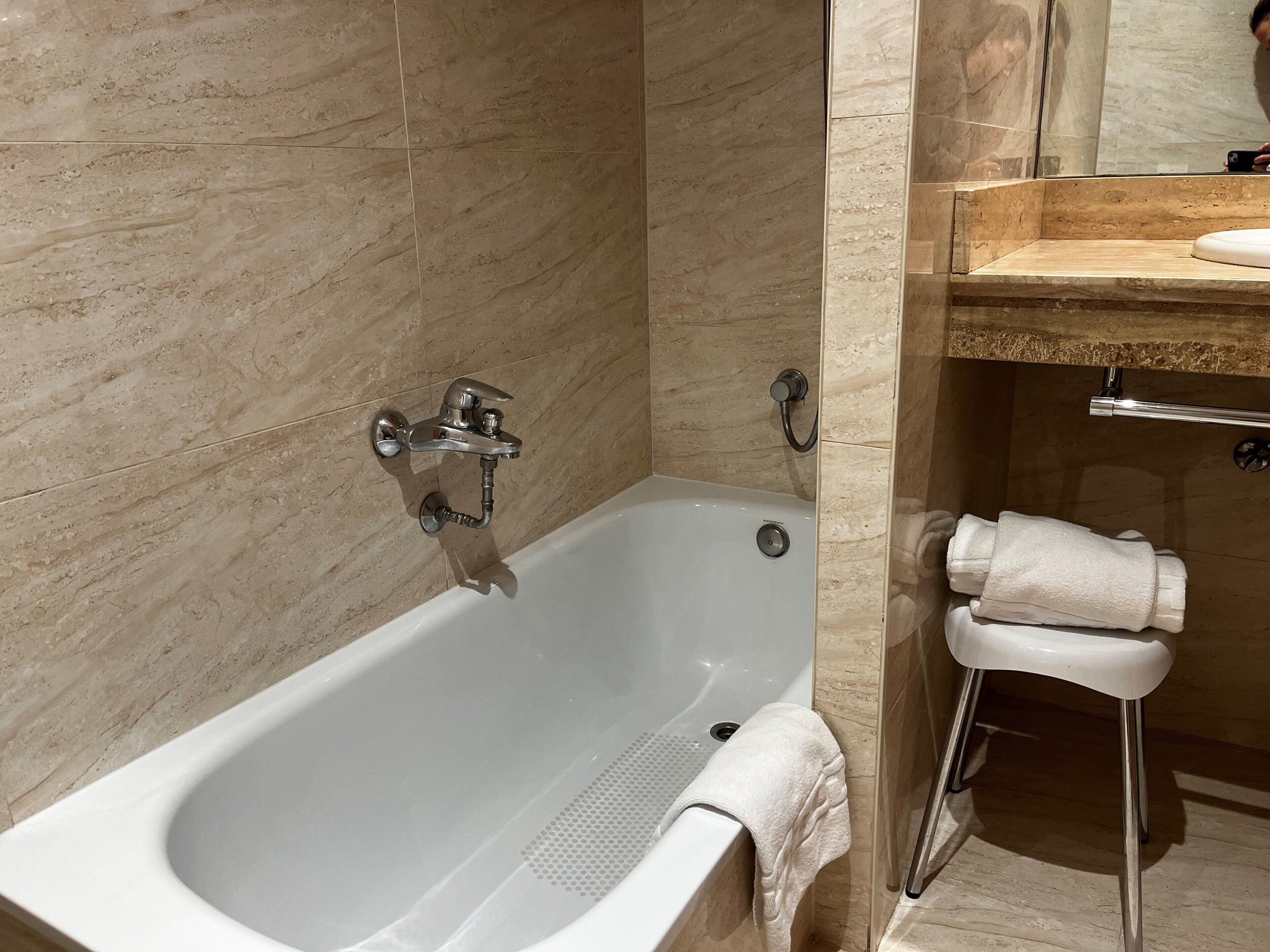 A modern bathroom with a bathtub, a shower, and a vanity with a towel rack.
