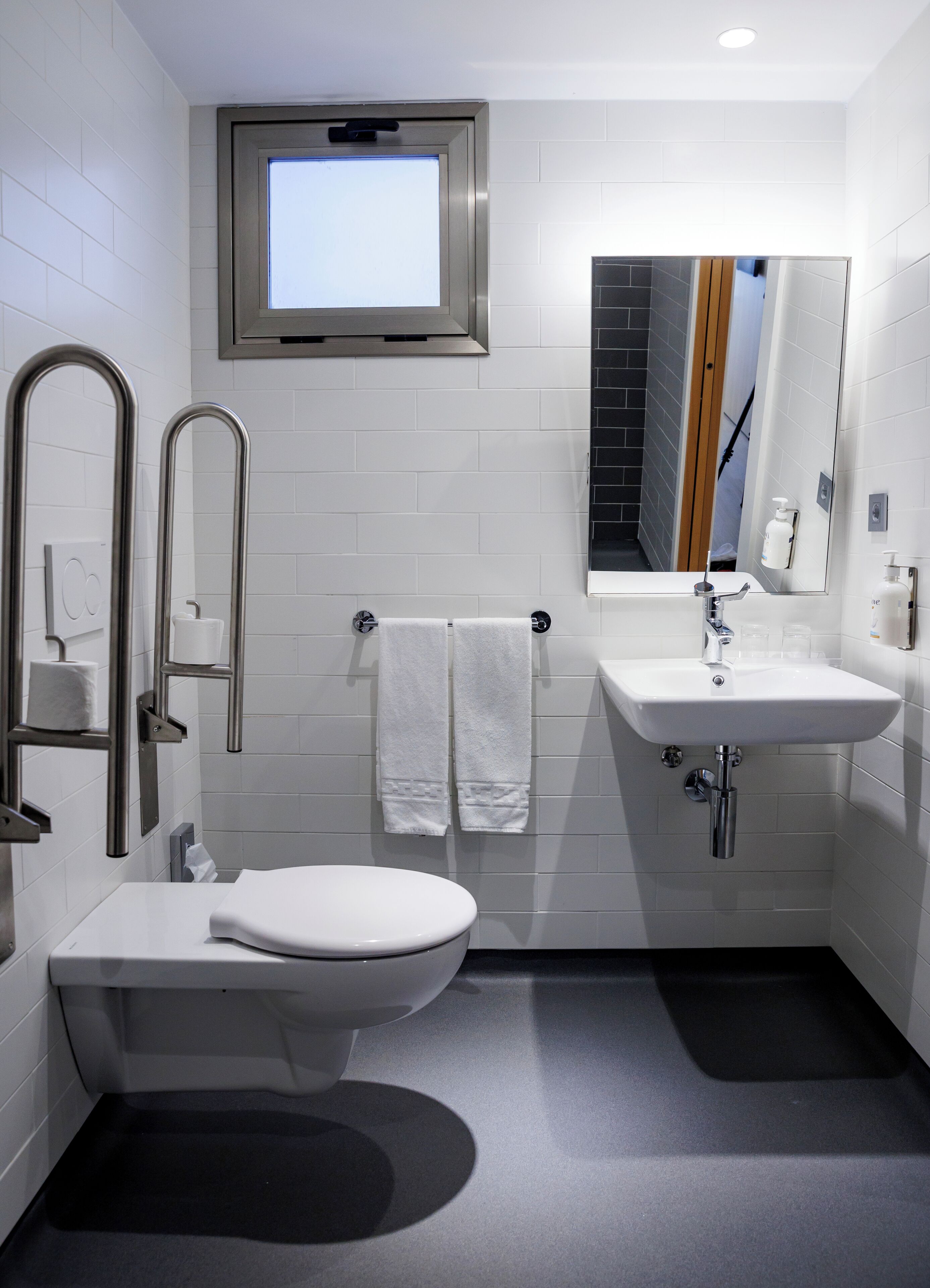 A modern bathroom with a toilet, bidet, sink, and a mirror.