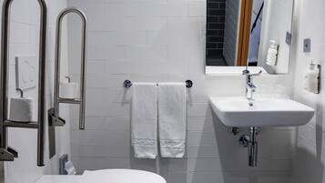 A modern bathroom with a toilet, bidet, sink, and a mirror.